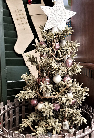 wool pine tree decorated with bulbs encircled by fence